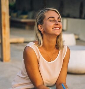 a smiling woman sitting | To be yourself in a world that is constantly trying to make you something else is the greatest accomplishment.