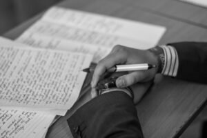 grayscale photography of person holding pen | i'mBiking magazine allows writers to submit their creative writing prompts and advertise their blog links for free.